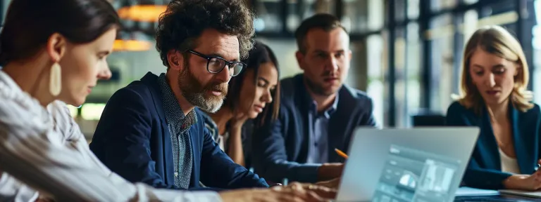 a group of business professionals engages in a focused discussion over a laptop displaying zatrox.com.